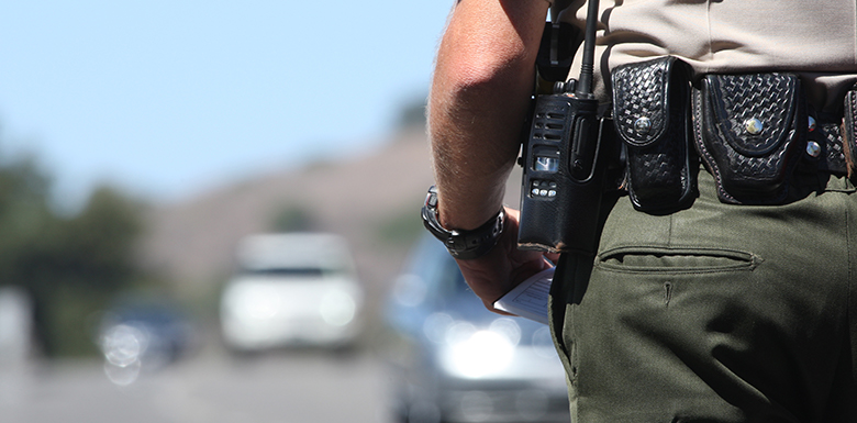 Police officer stepping up to car on highway with ticket