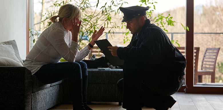 Police officer crouching down to talk to seated woman